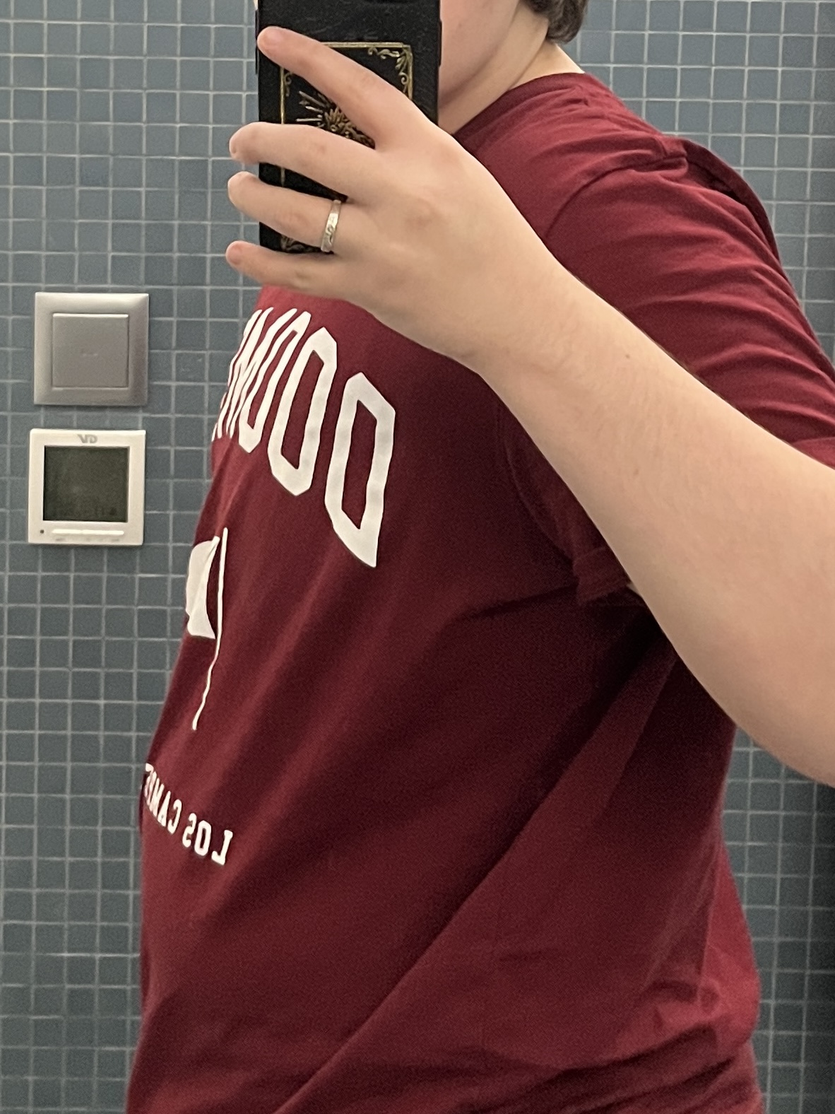 Trans man wearing a red shirt facing sideways